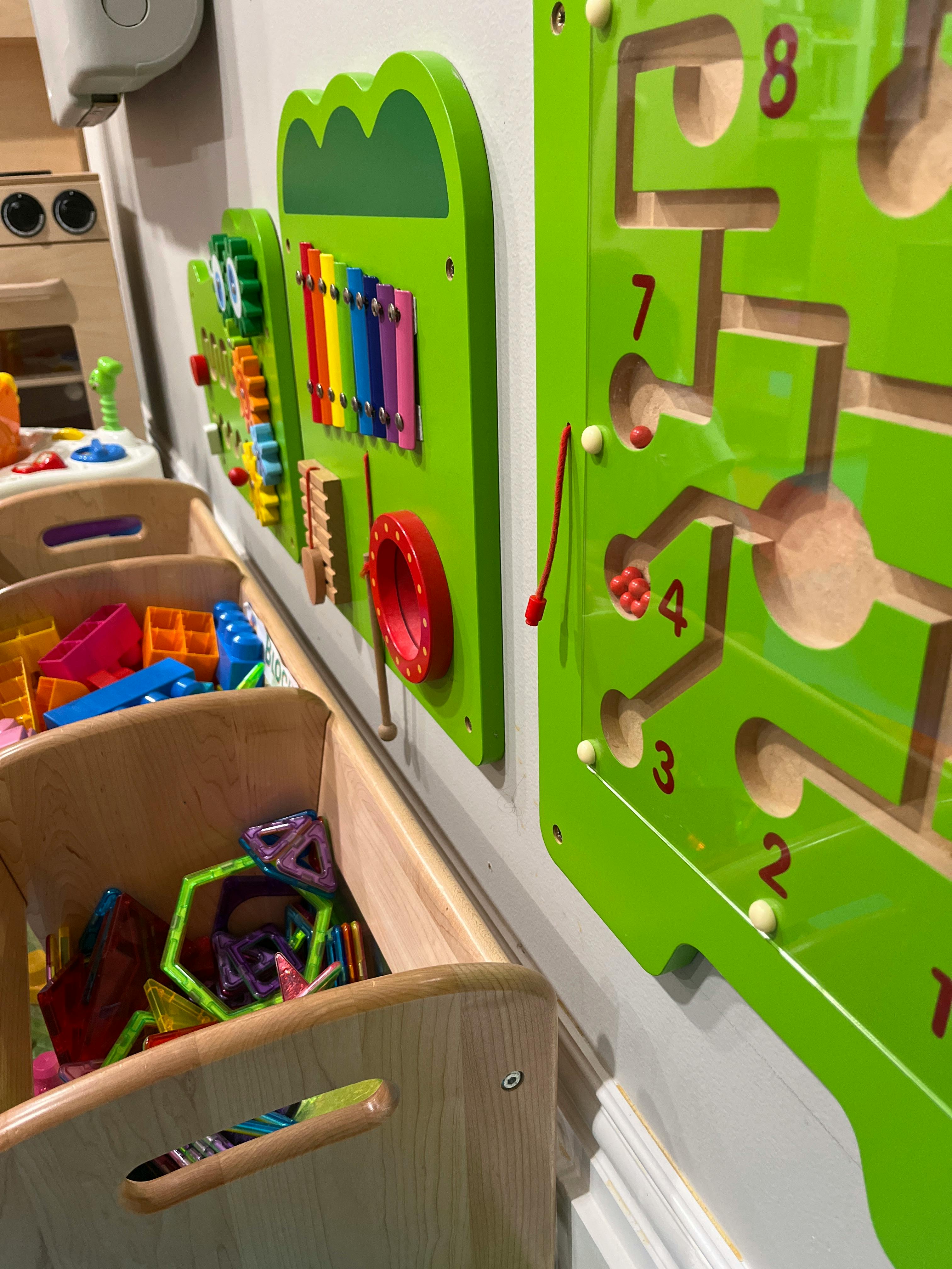 Wall-mounted educational activity boards with bins of colorful toy blocks