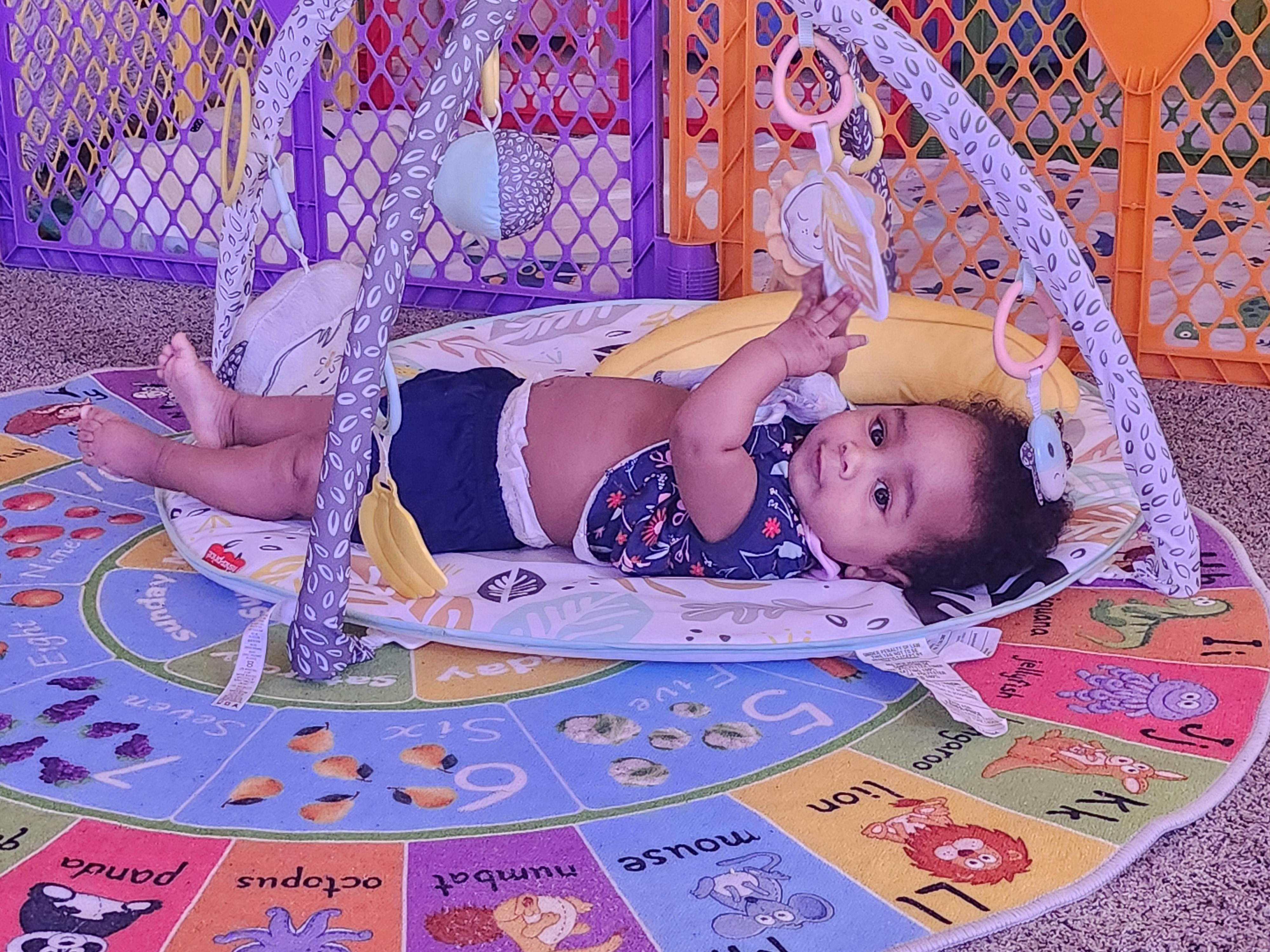 Child lying on a playmat reaching for a toy