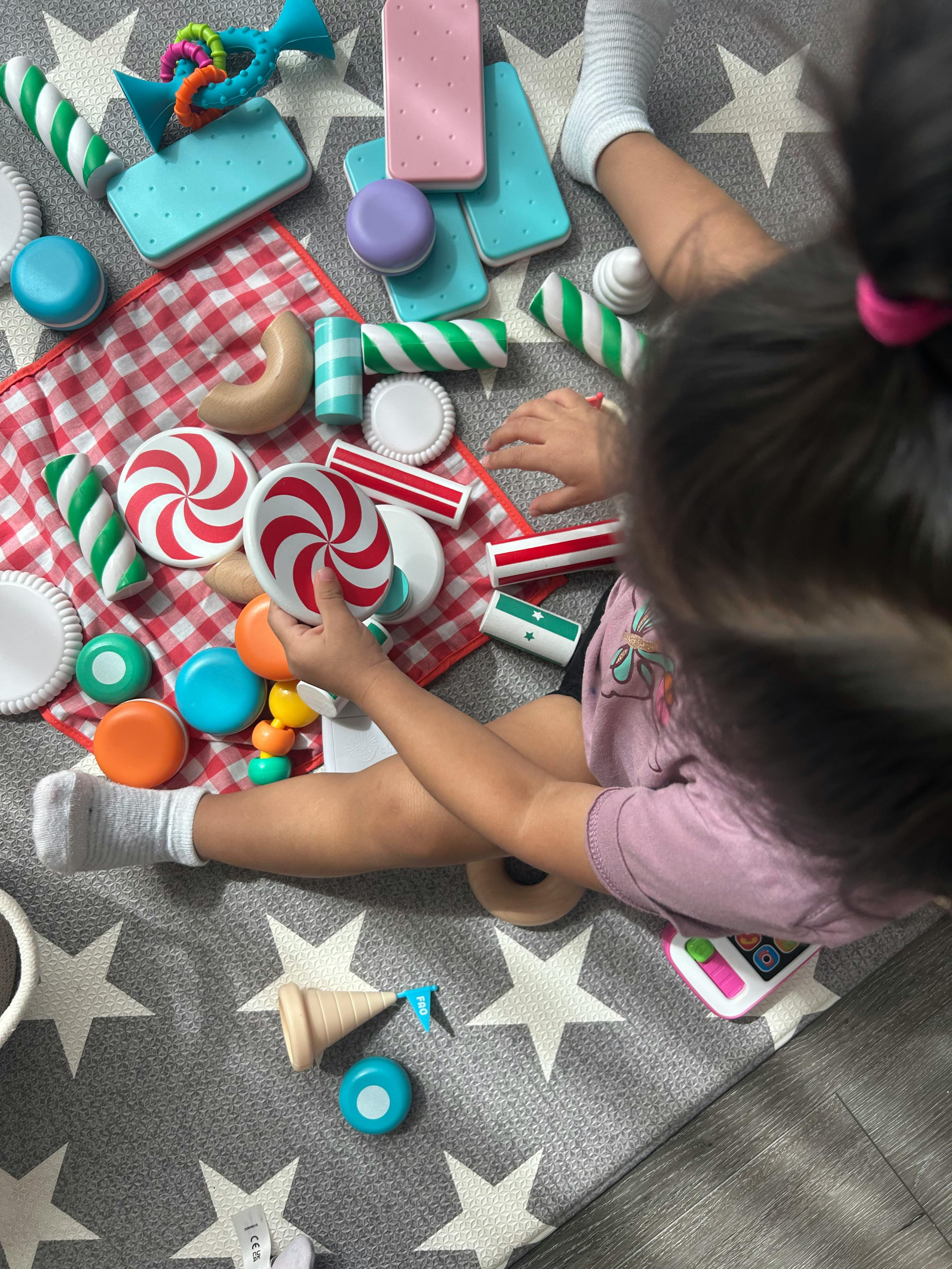 Child playing with toy candies and blocks on a star-patterned rug