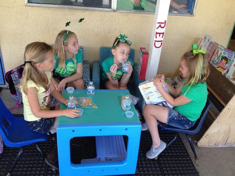 Four children sitting around a table with drinks and snacks