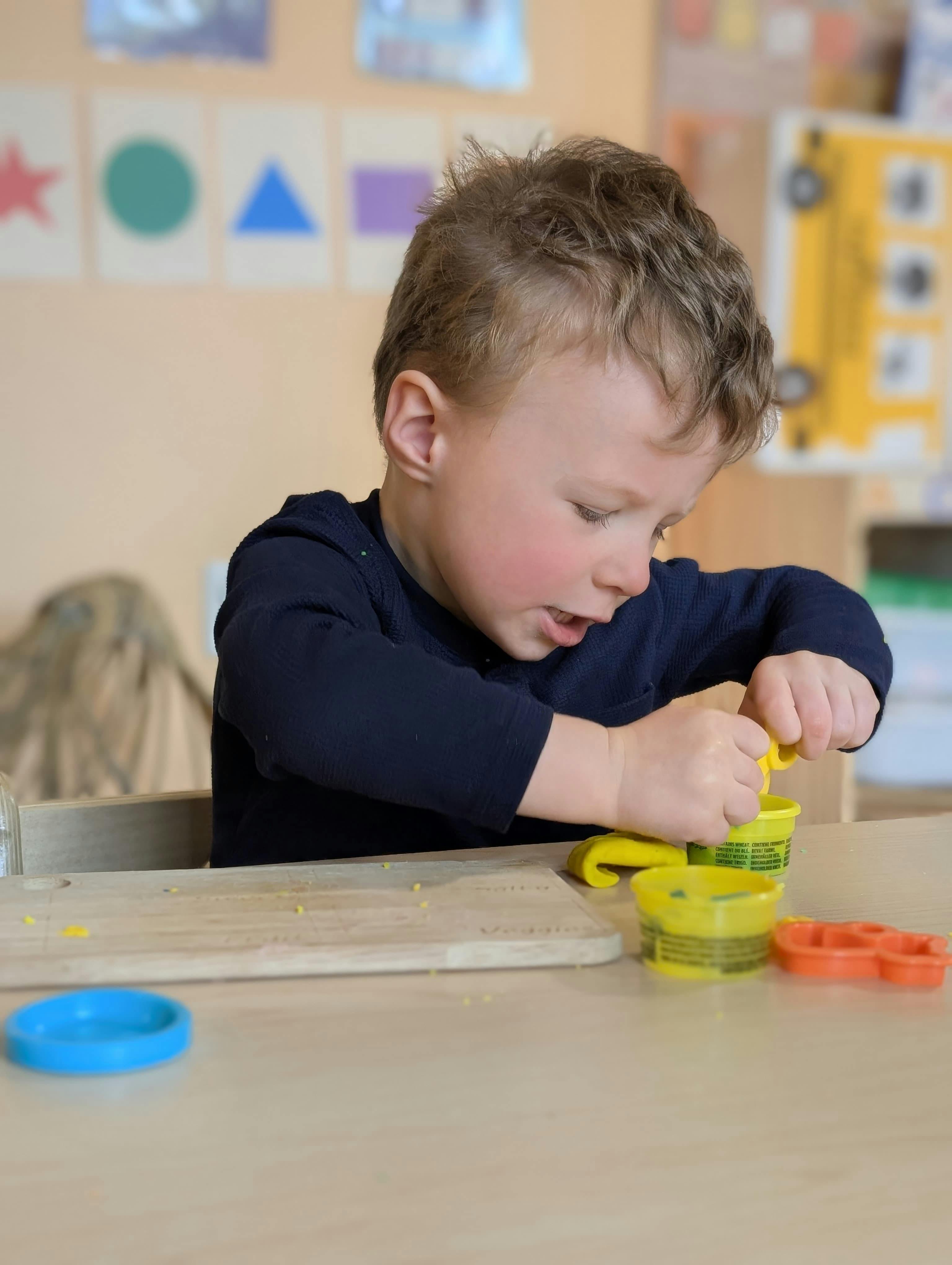 Child pressing yellow playdough in a classroom