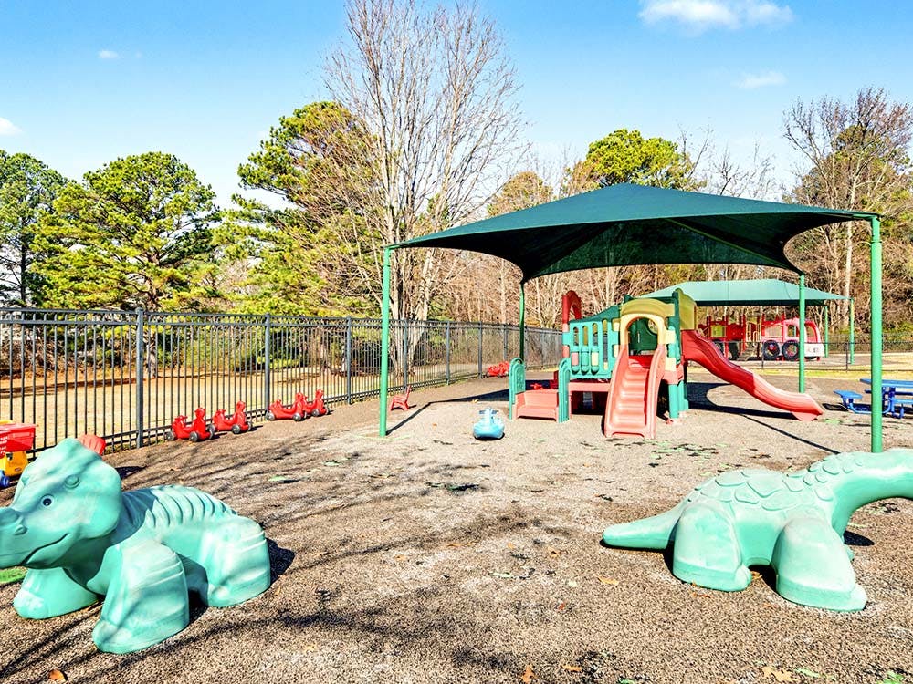 Playground with slides, climbers, ride-on toys, and shade canopy