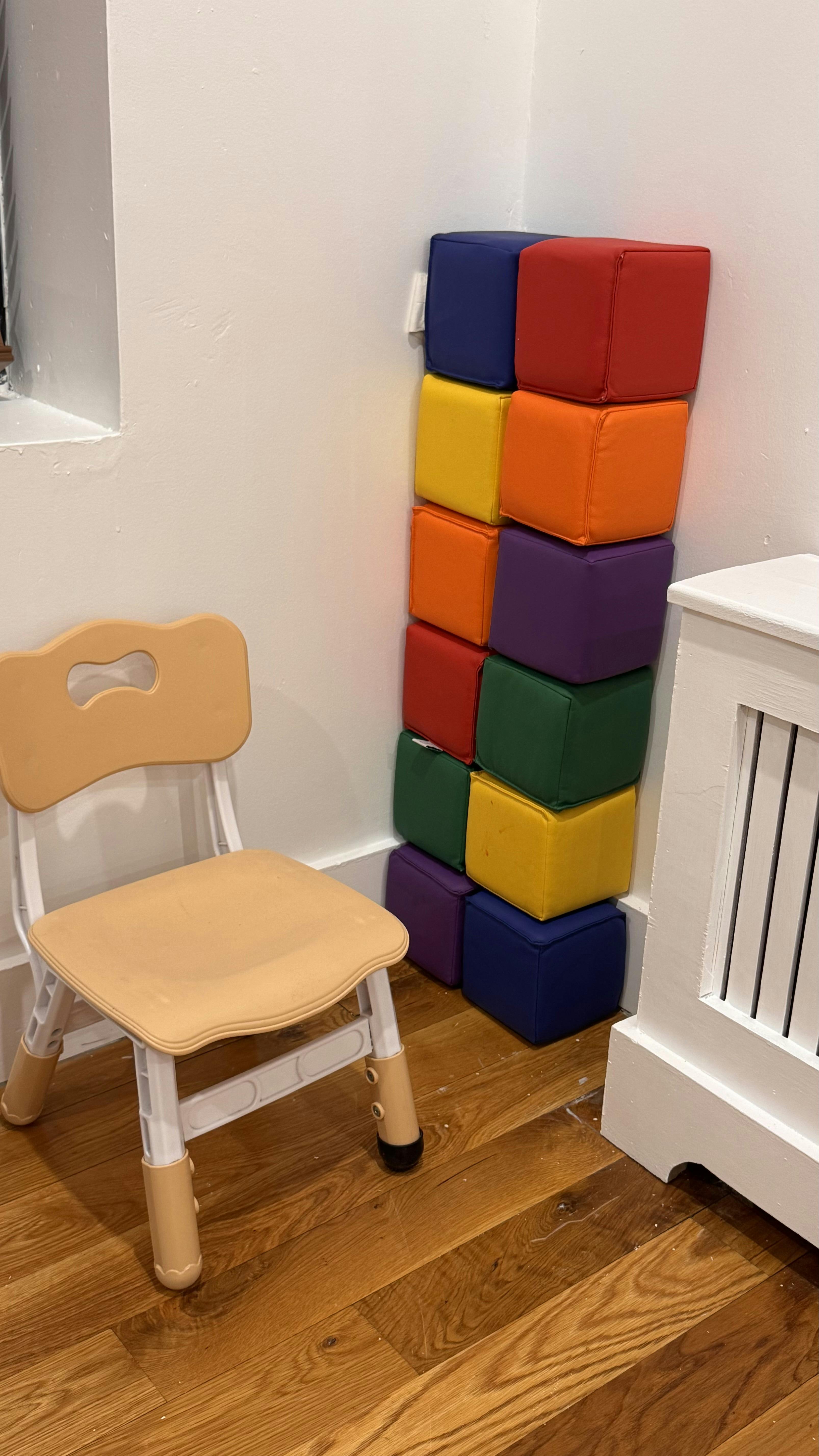 Small chair next to a stack of colorful soft play blocks