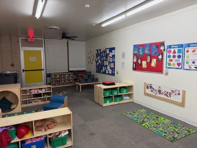 Classroom with cubbies, toys, and educational posters on the wall