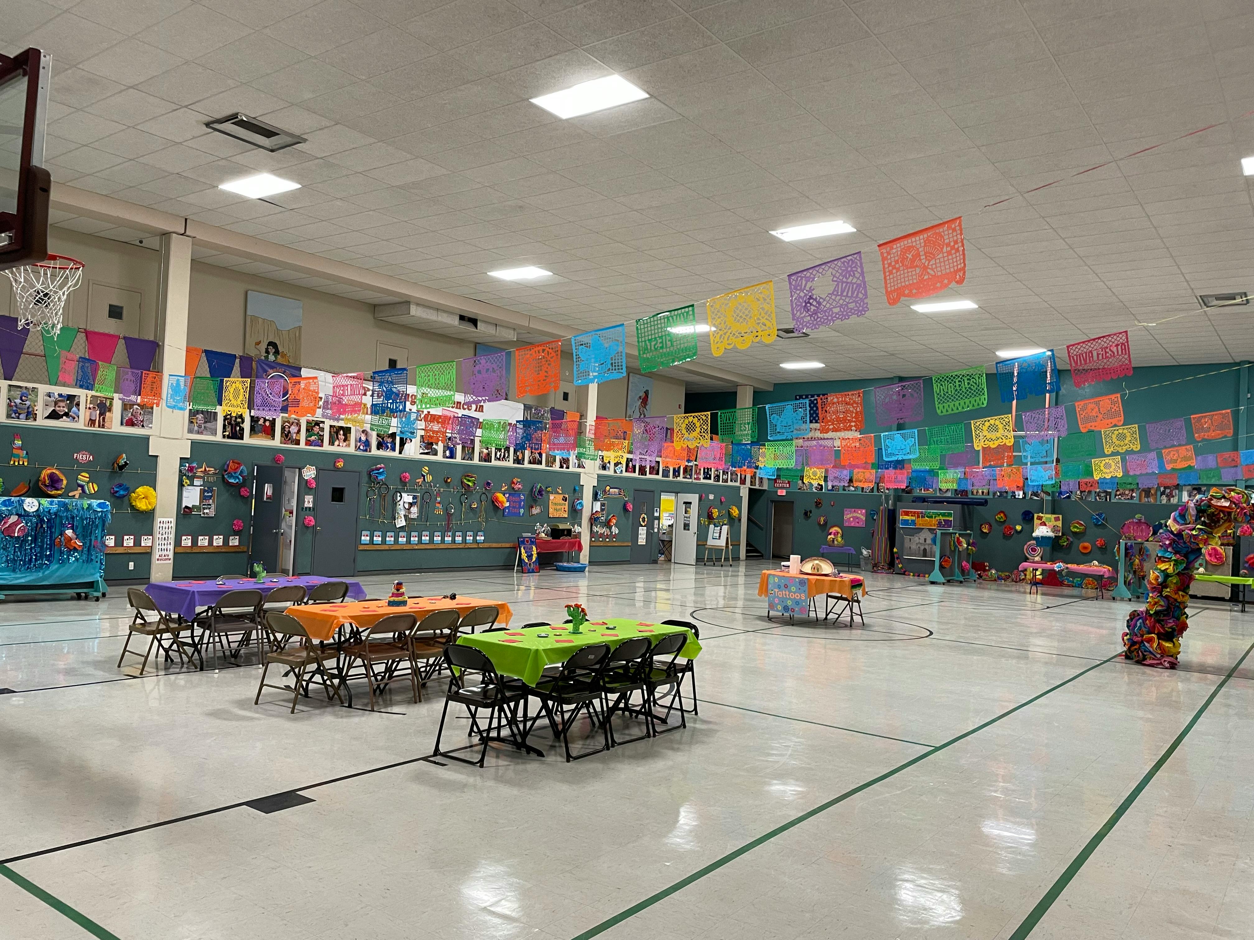 Gymnasium decorated with colorful banners and tables with tablecloths