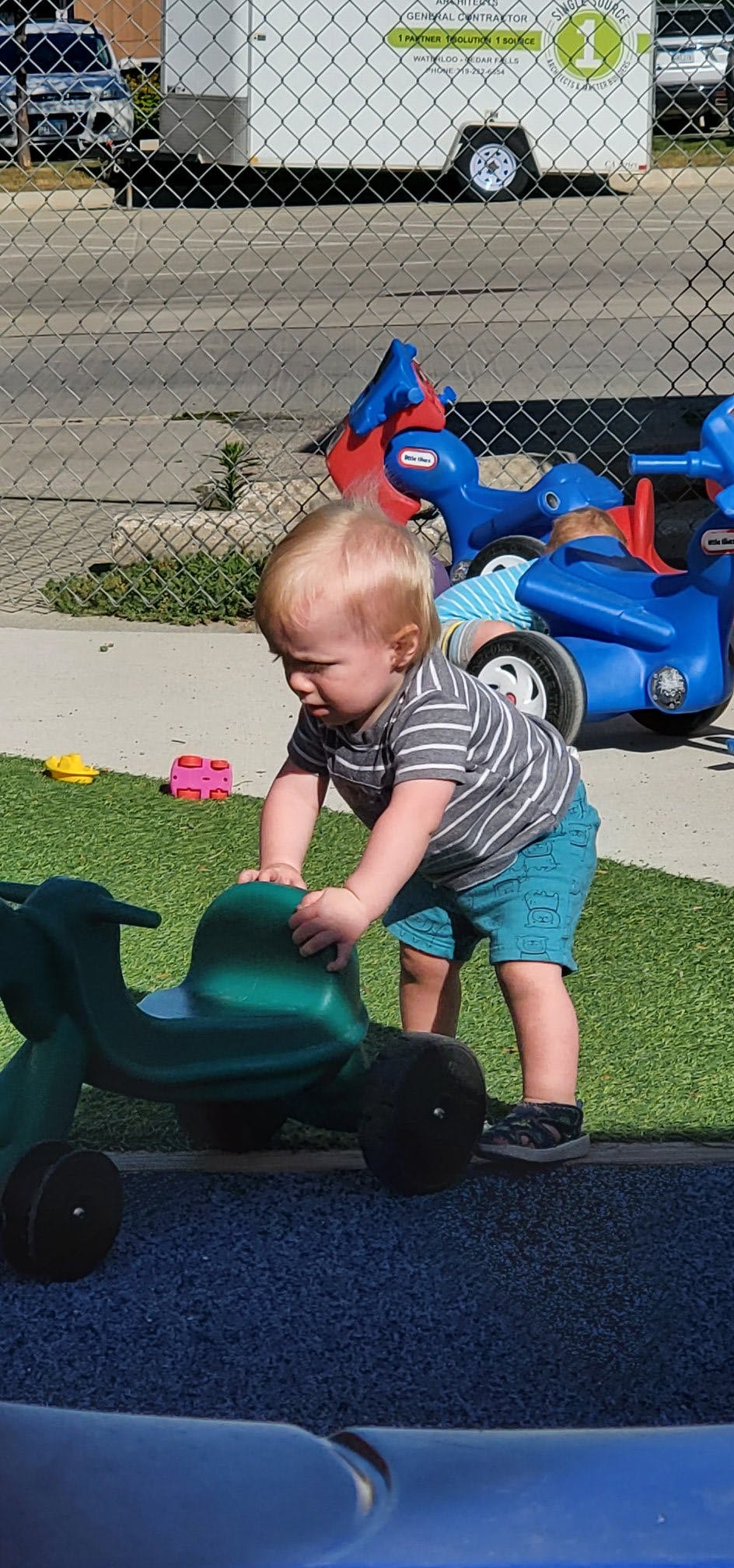 Child playing with a green ride-on toy