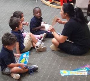 Adult and children sitting on floor looking at books