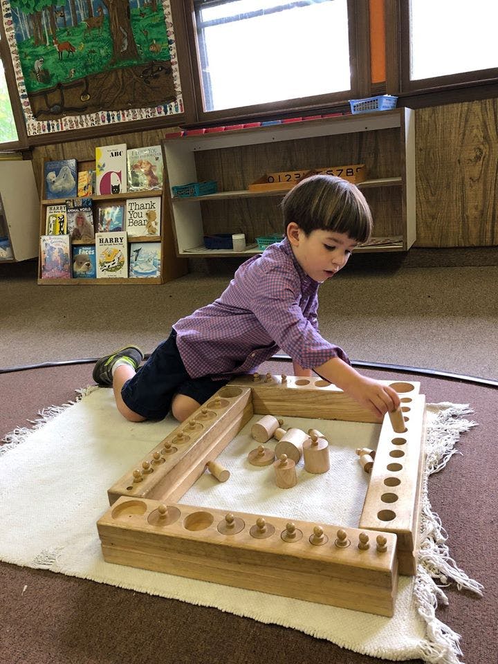 Child playing with wooden blocks and a wooden puzzle on a rug