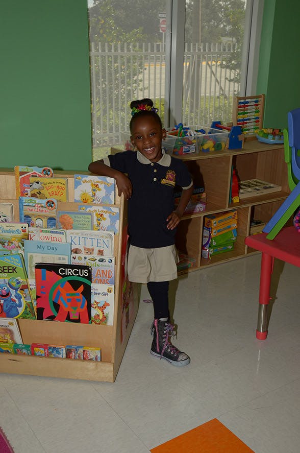 Child standing next to a bookshelf filled with books