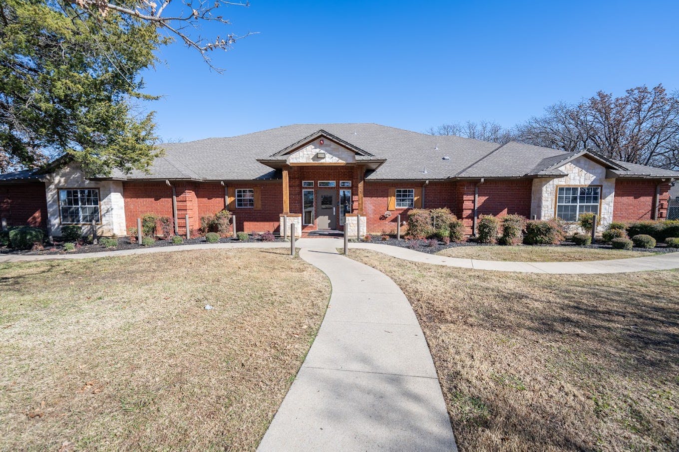 Single story brick building with a concrete walkway leading to the entrance