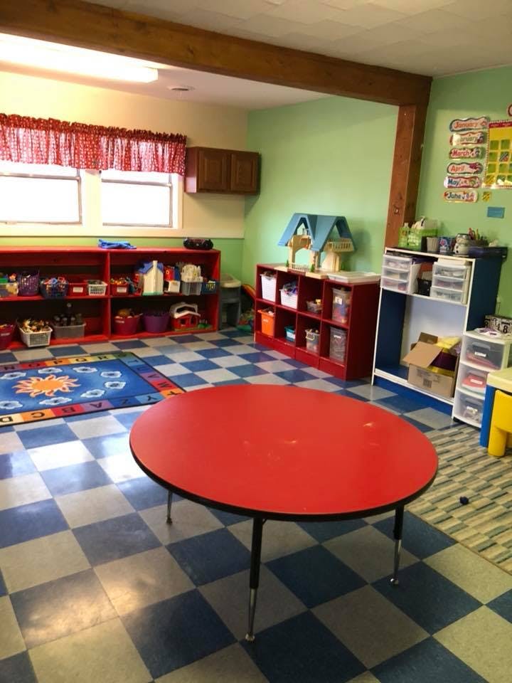 Classroom with red table, blue and white checkered floor, and red shelves