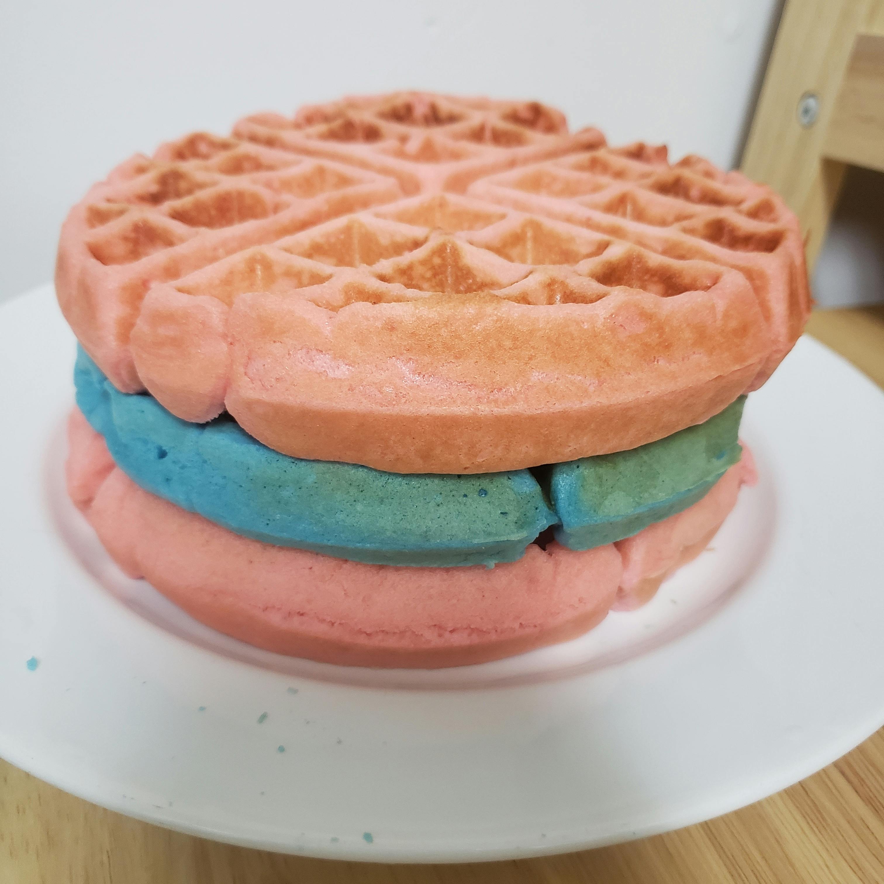 Stacked pink and blue waffles on a white plate