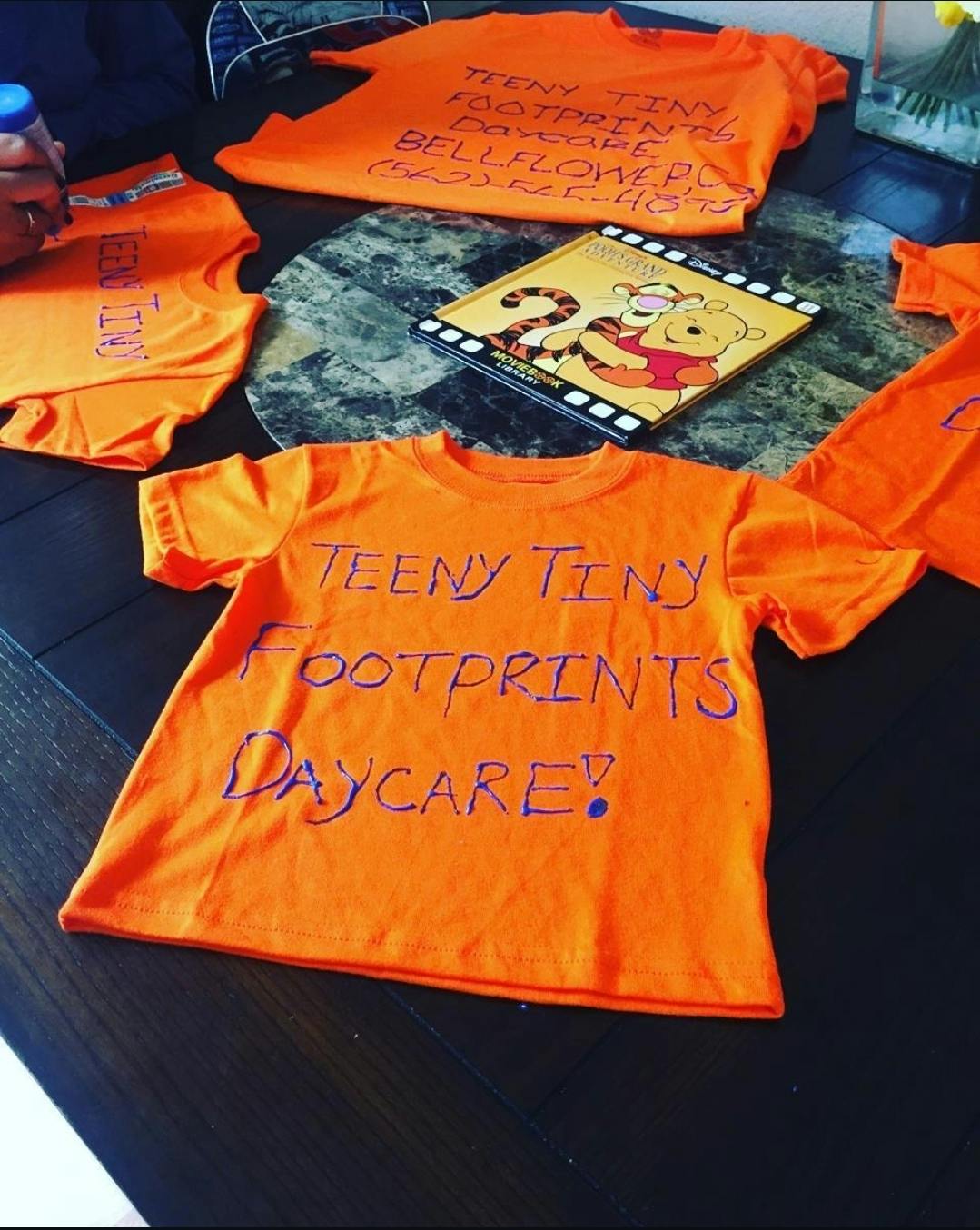Orange t-shirts with Teeny Tiny Footprints Daycare written on them