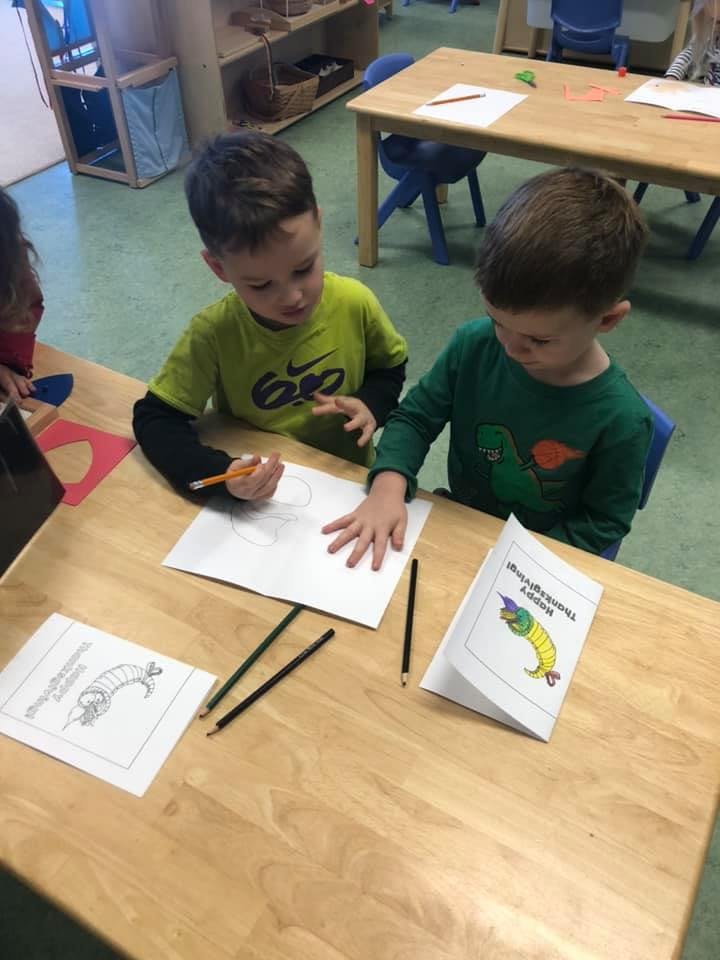 Two children drawing at a table in a classroom