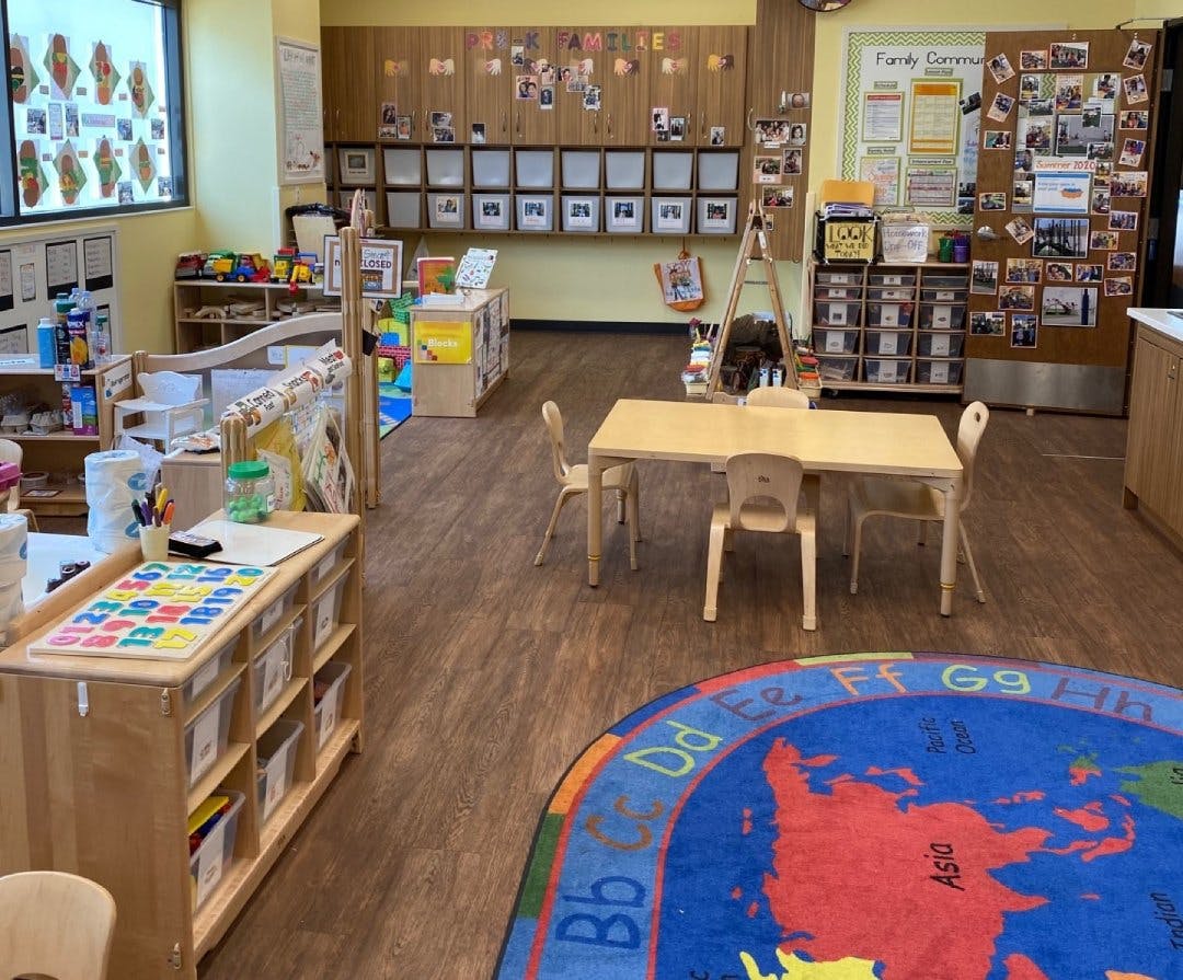 Classroom with small tables and chairs, and a colorful world map rug
