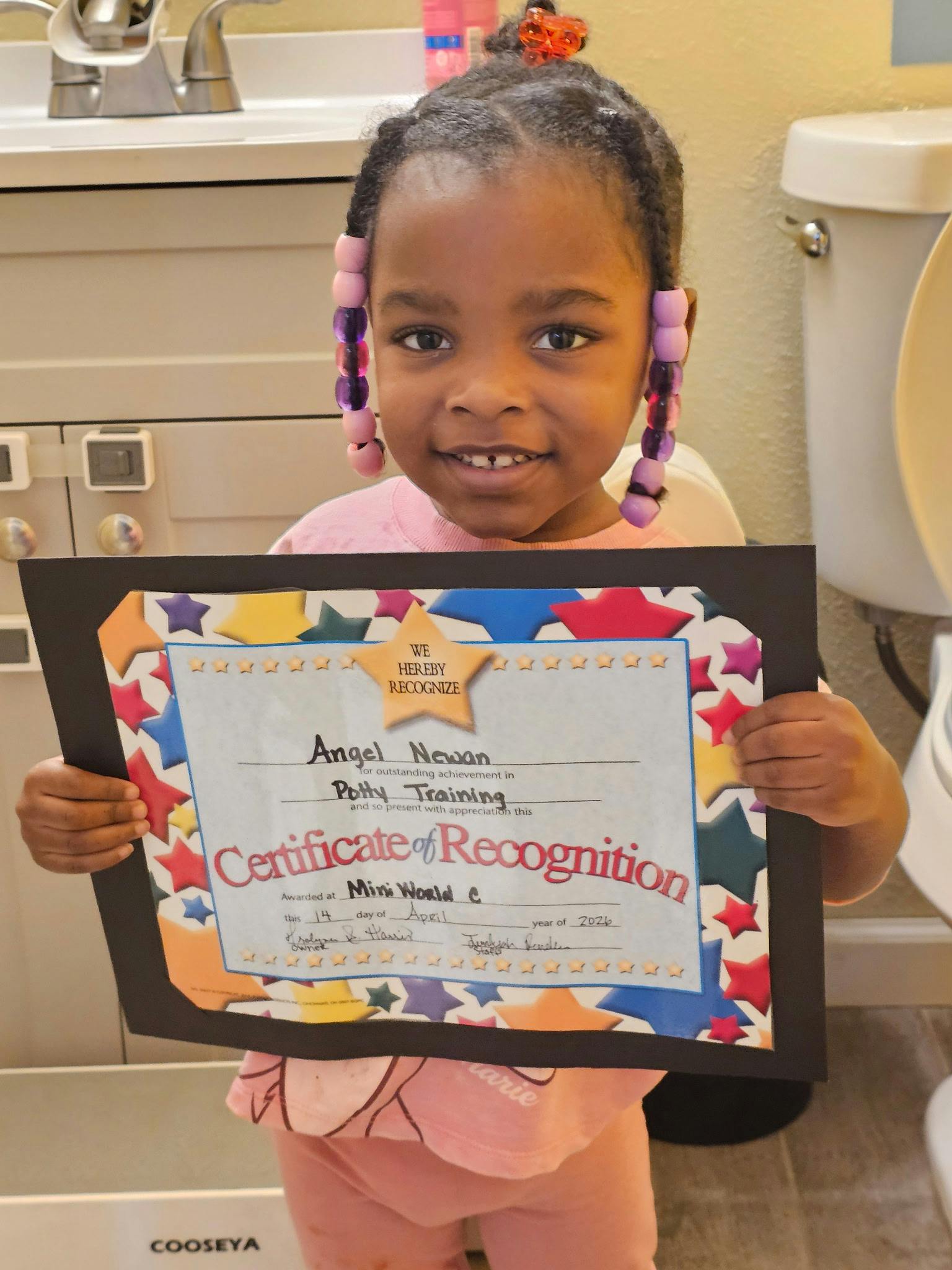 Child holding a potty training certificate of recognition