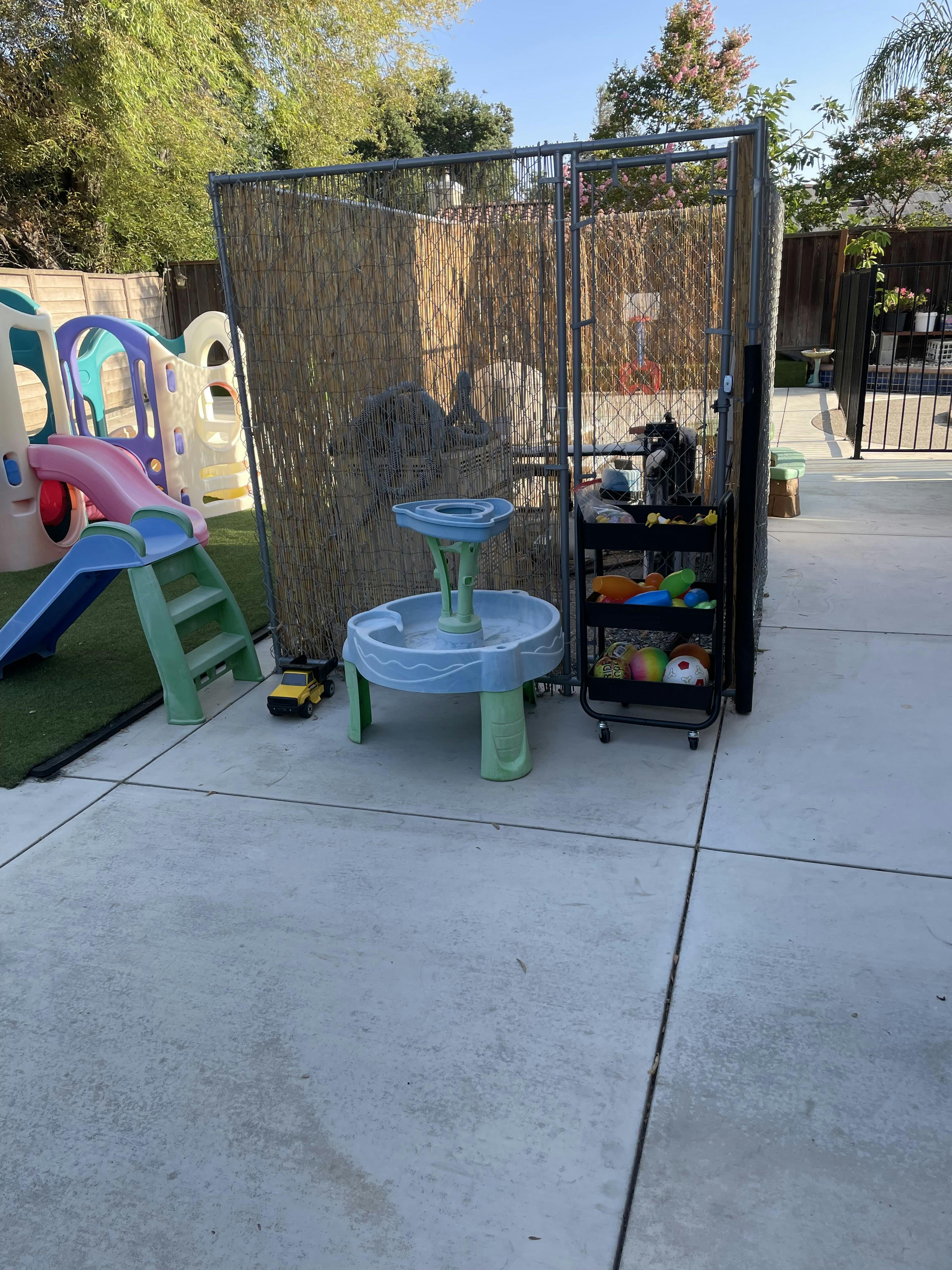 Plastic children playground equipment and a storage cart on a patio
