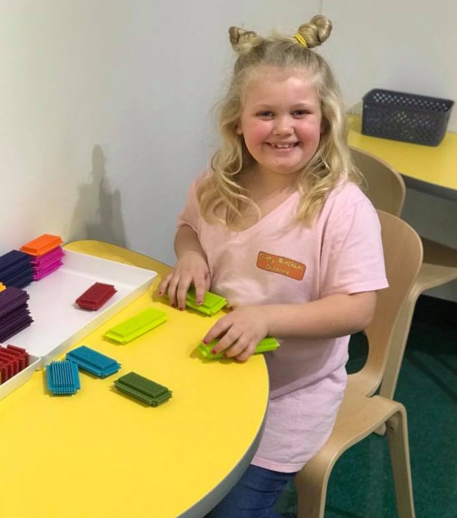Child playing with colorful blocks at a yellow table