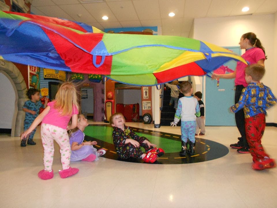 Adult and children playing with a colorful parachute indoors