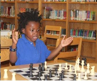 Child playing chess with hands raised