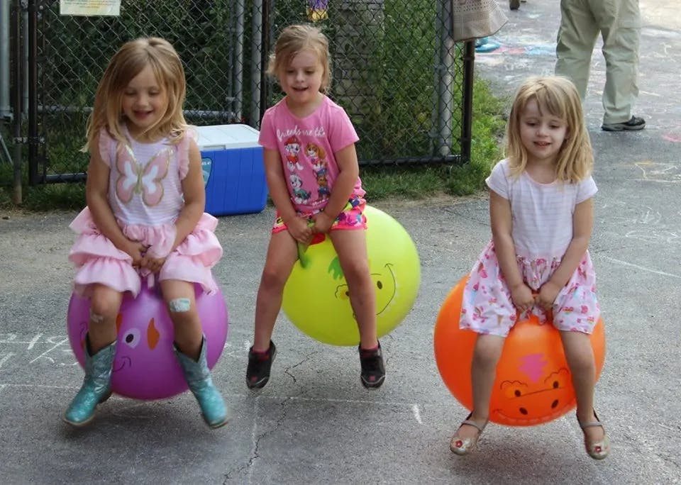 Three children bouncing on hopper balls