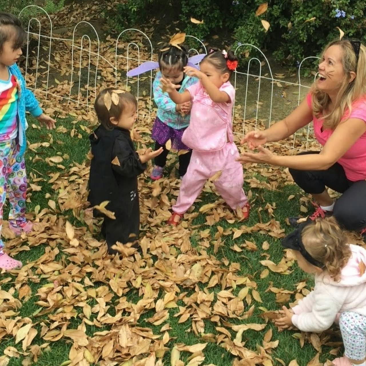 Adult and children playing with leaves outdoors