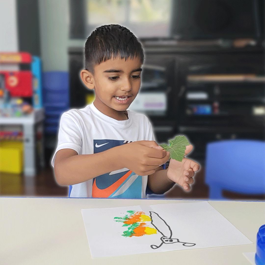 Child holding a leaf over a drawing of a carrot