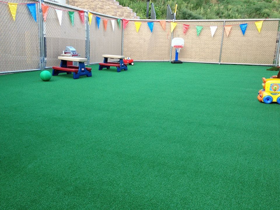 Play area with green turf, small picnic tables, and toys