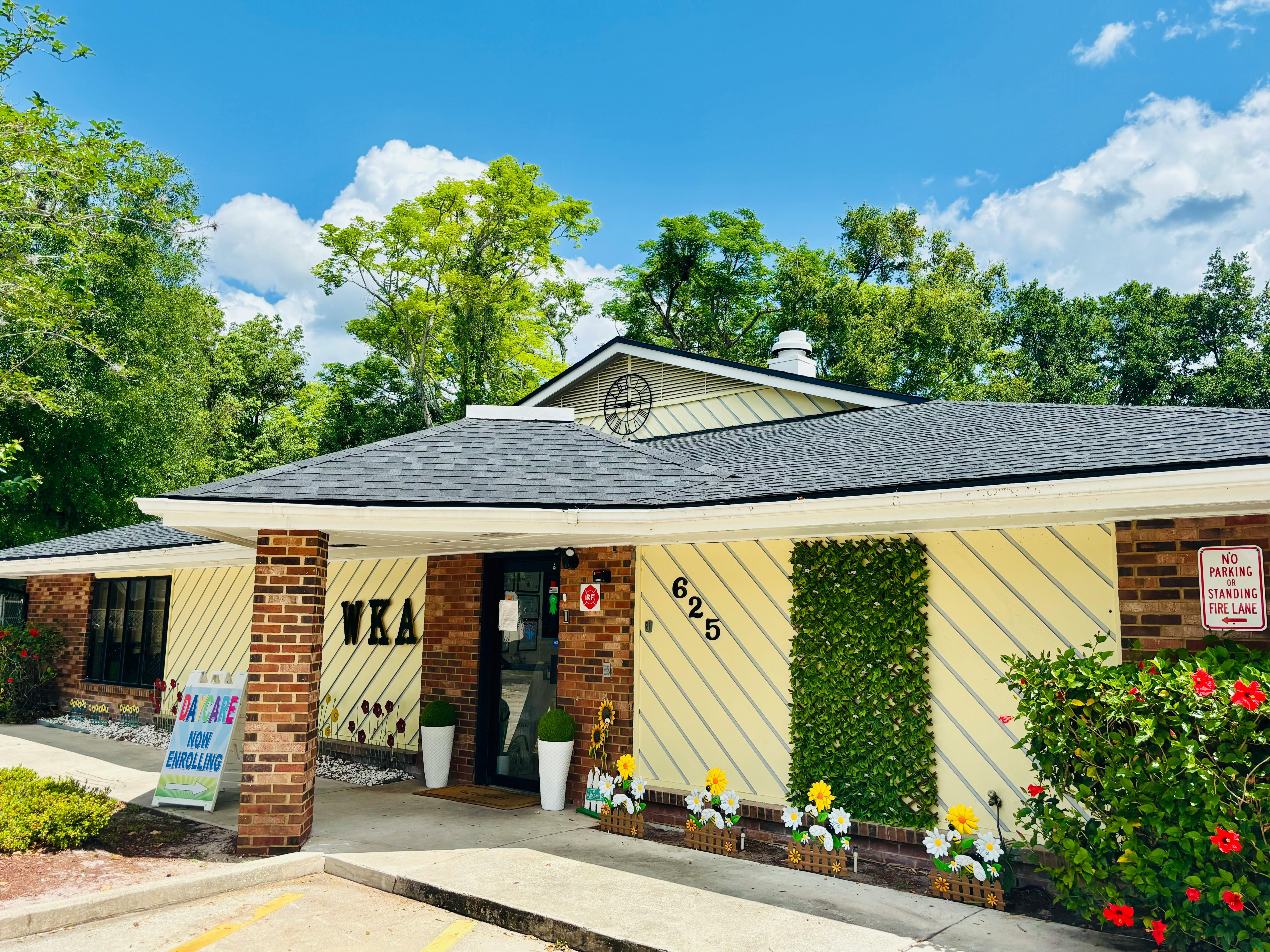 Exterior of a building with yellow siding, brick columns, and a dark roof