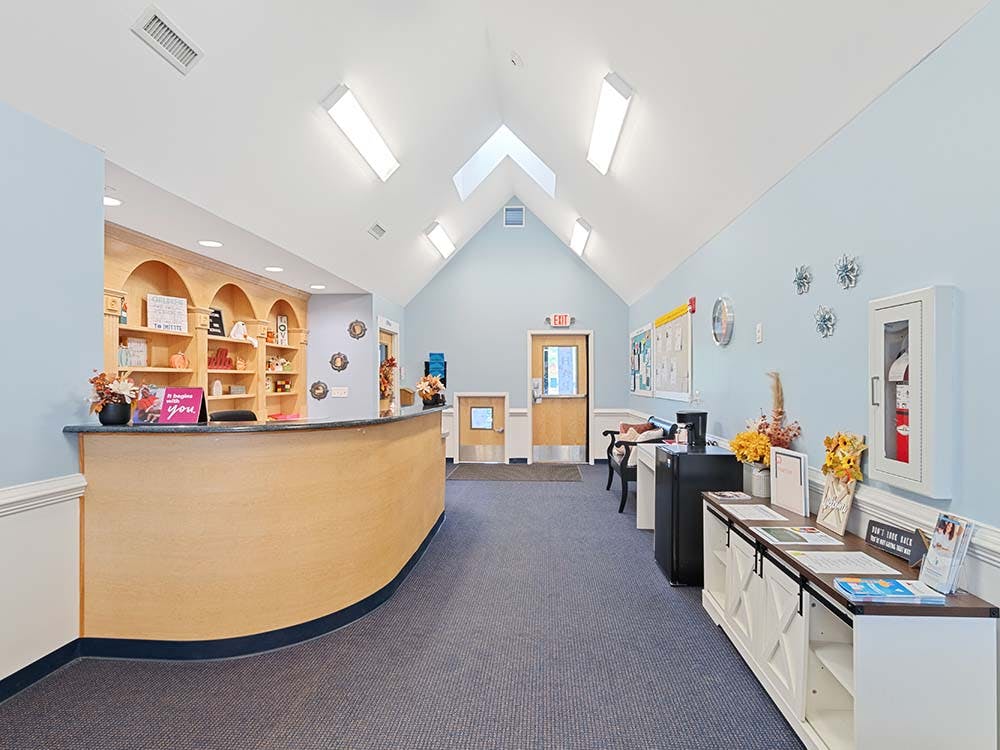Reception area with a light wood curved desk and light blue walls