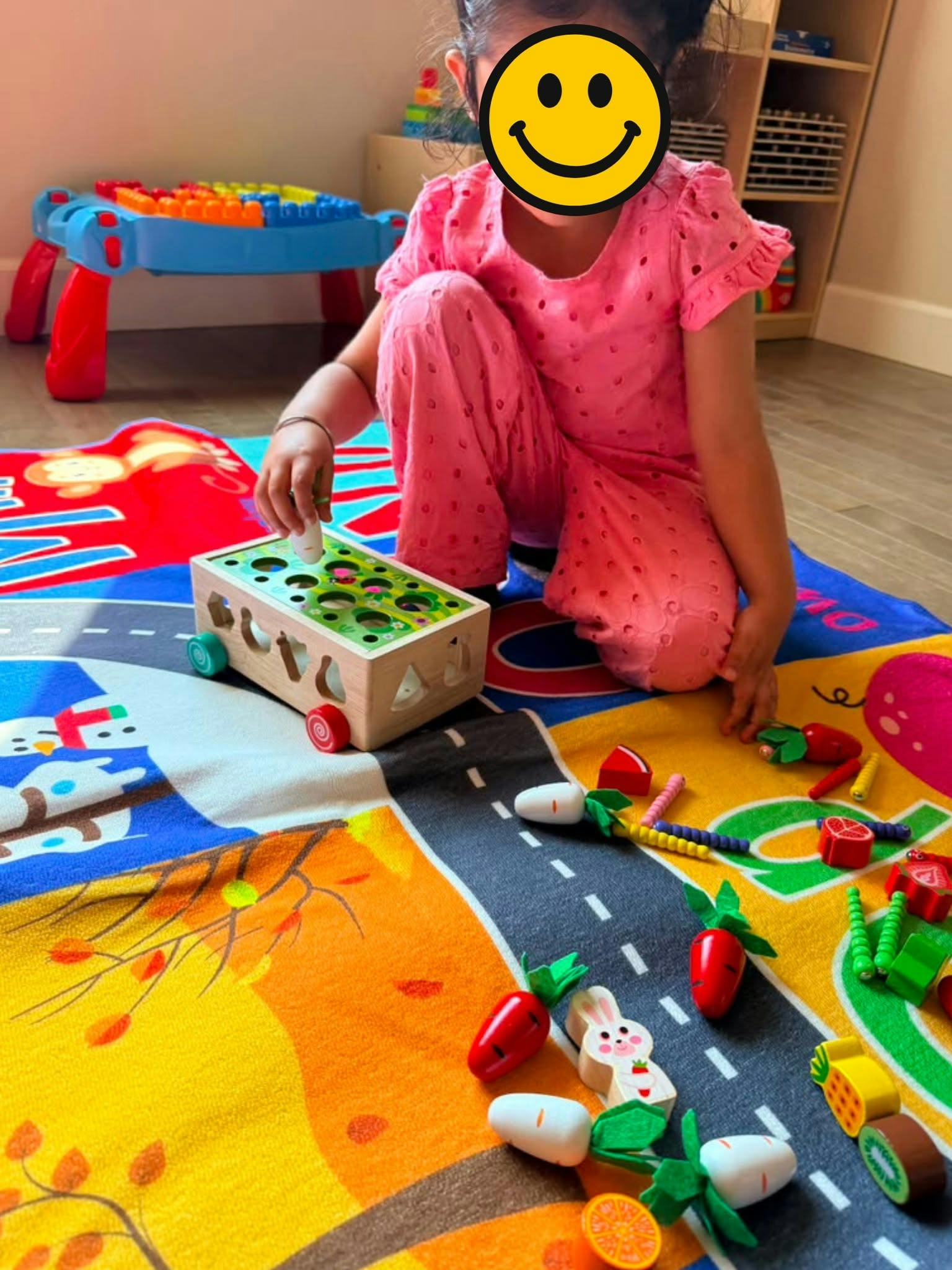 Child playing with a wooden vegetable sorting toy on a colorful play mat