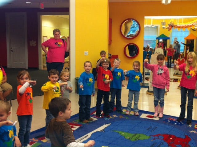 Children standing on a map rug in a classroom