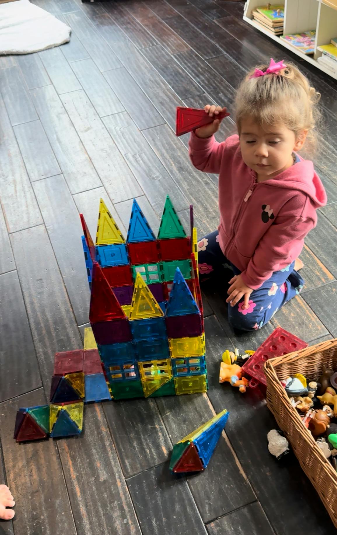 Child kneeling on floor playing with colorful magnetic building blocks