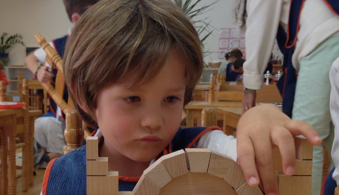 Child playing with wooden blocks in a classroom