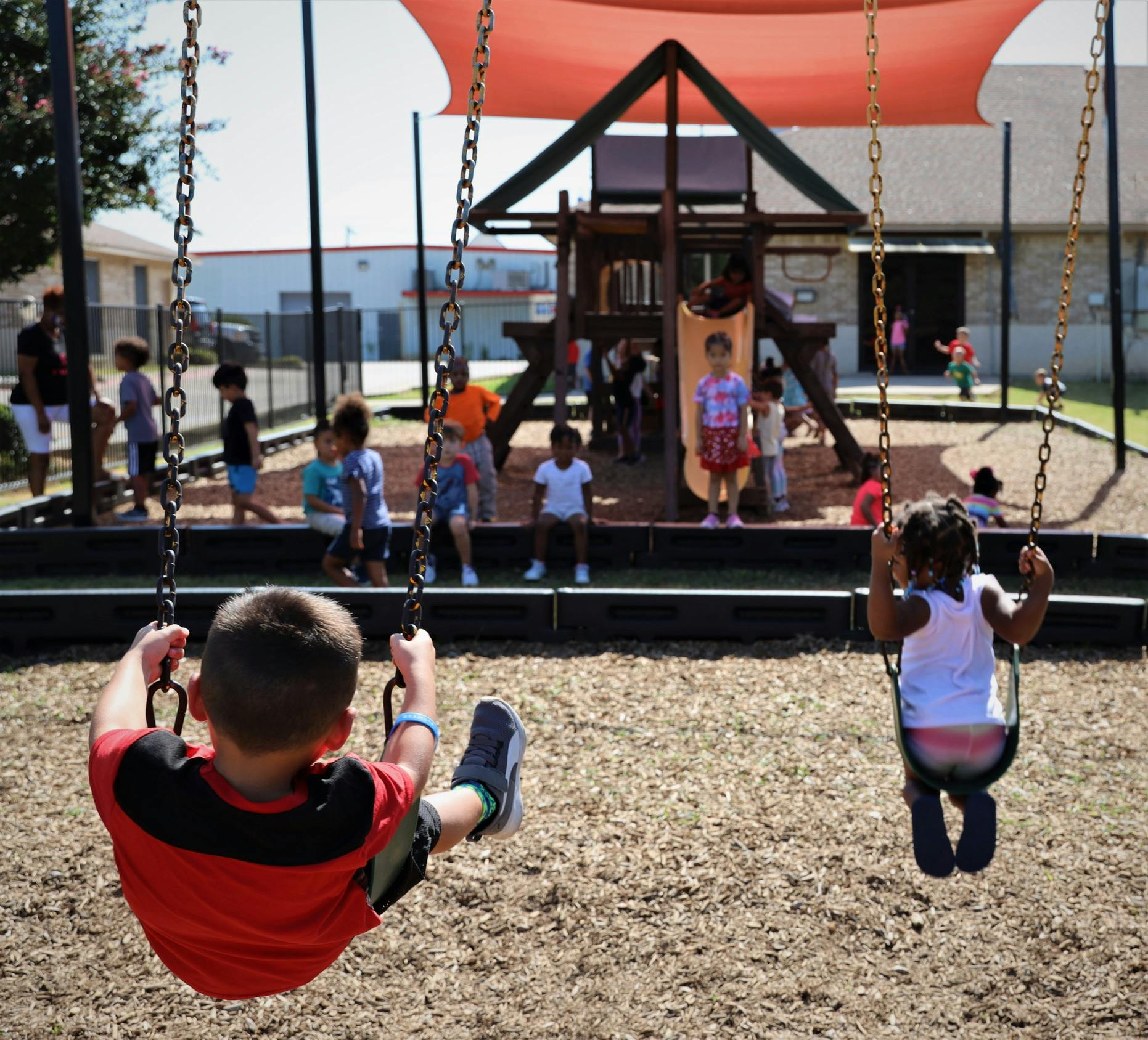 Children playing on swings and a playground structure