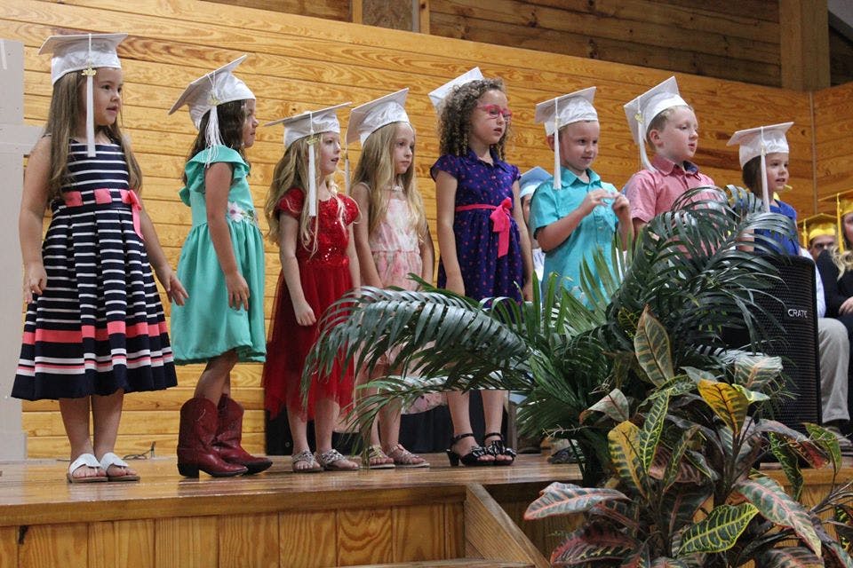 Children in graduation caps standing on a stage