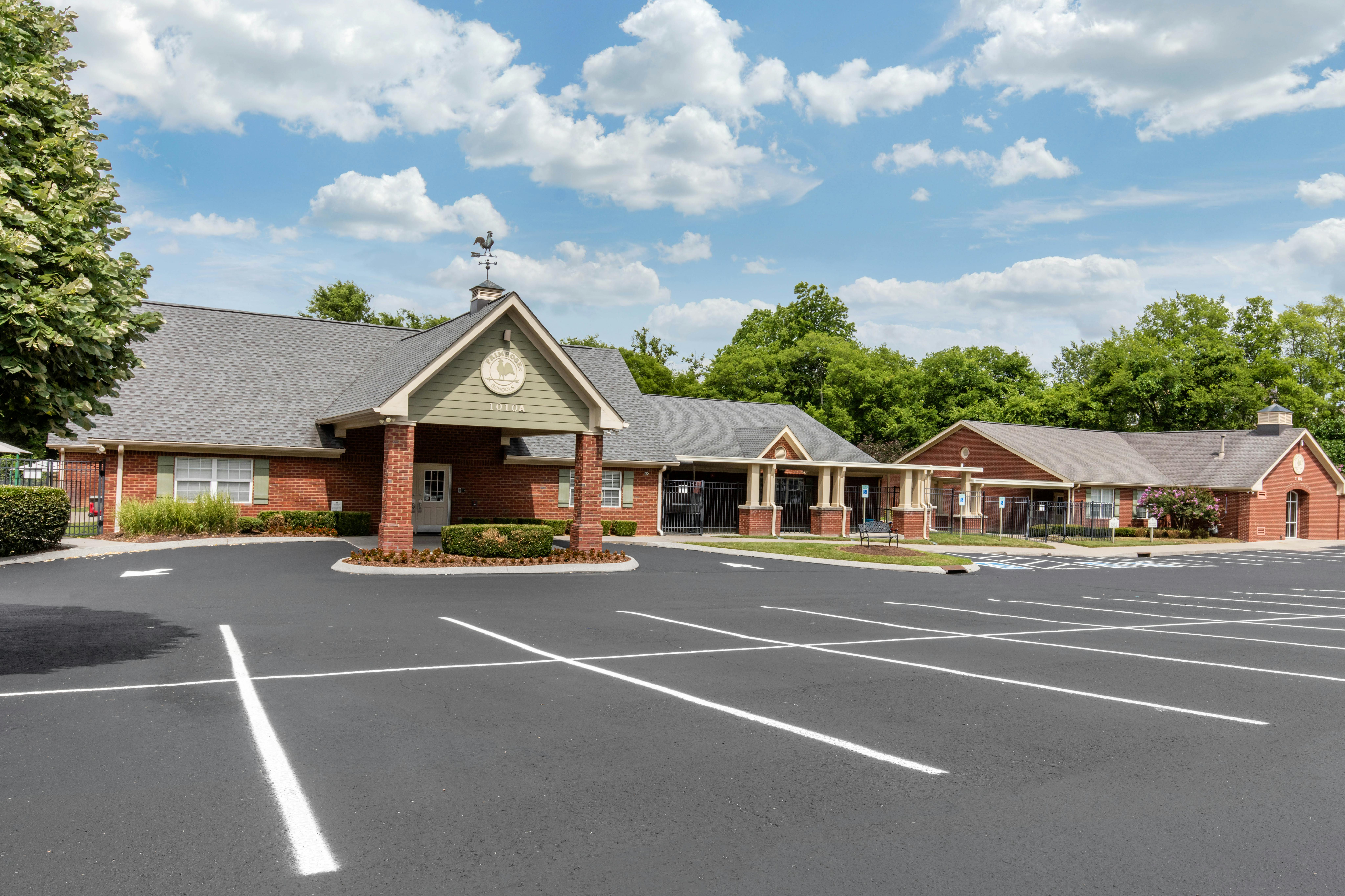 An empty parking lot in front of a brick building with a sign that reads "Primrose Schools"