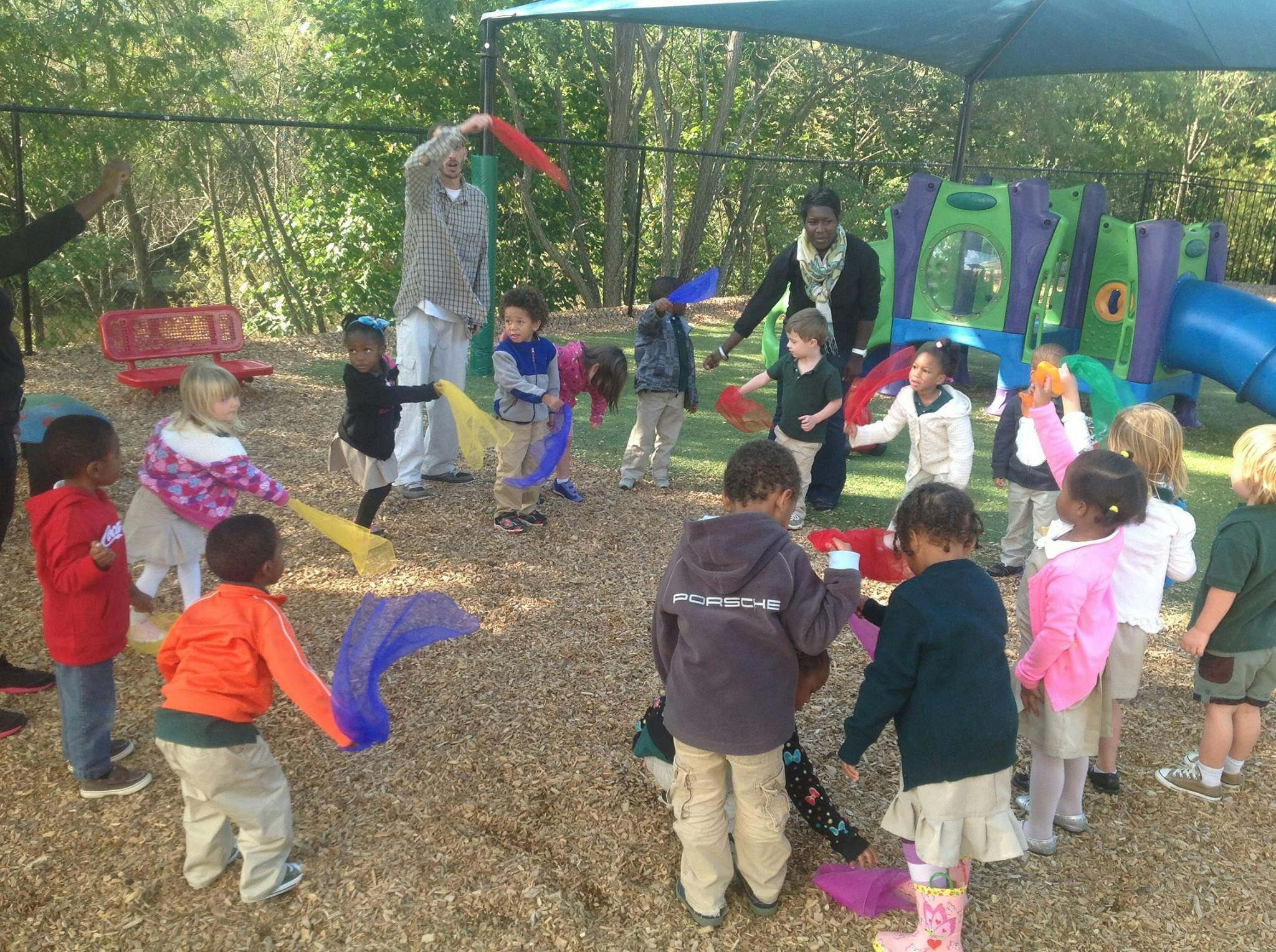 Adults and children playing with colorful fabric streamers outdoors