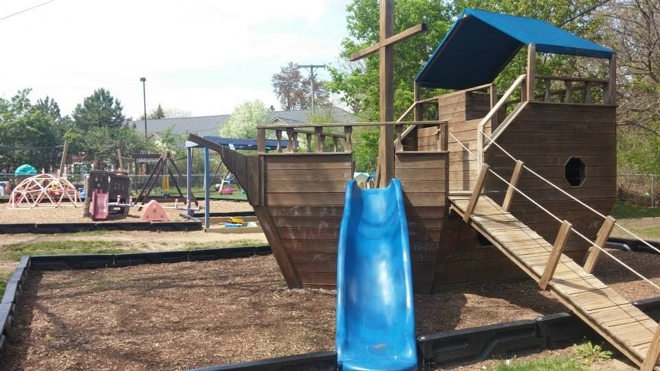 Playground with a wooden ship structure and blue slide