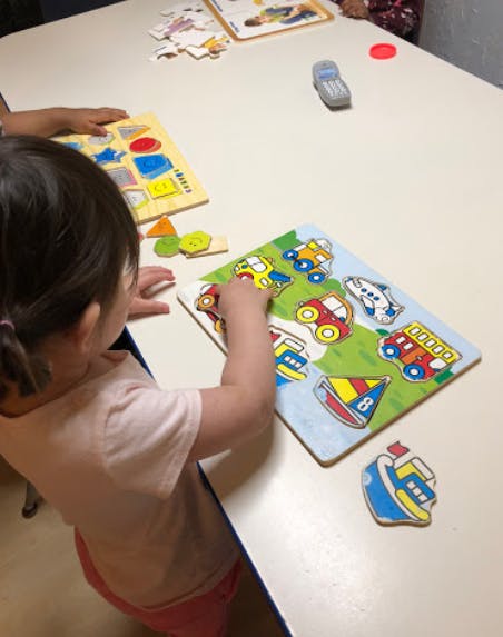 Child playing with a vehicle puzzle on a table