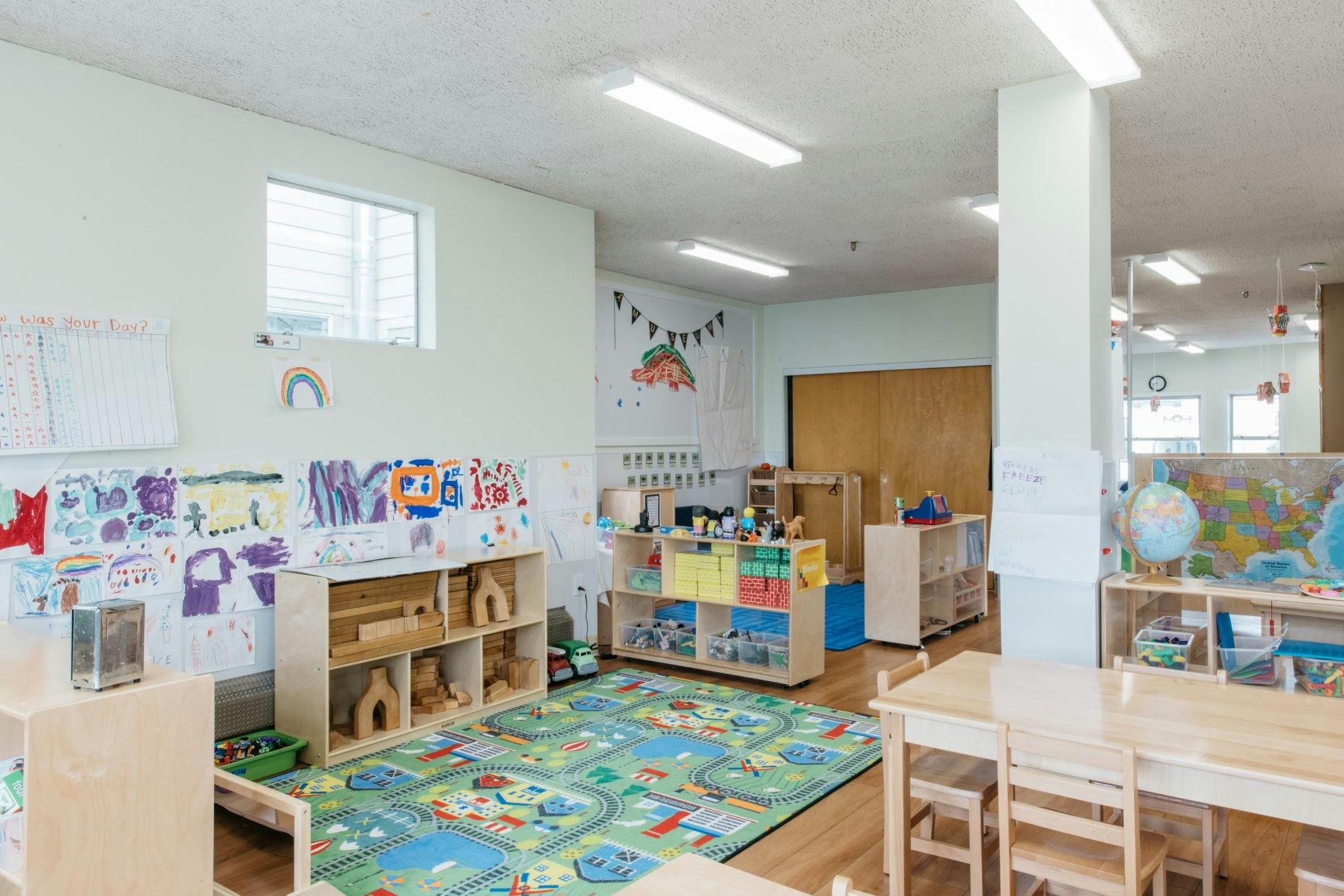 Children's classroom with artwork on walls, toys, and small tables and chairs