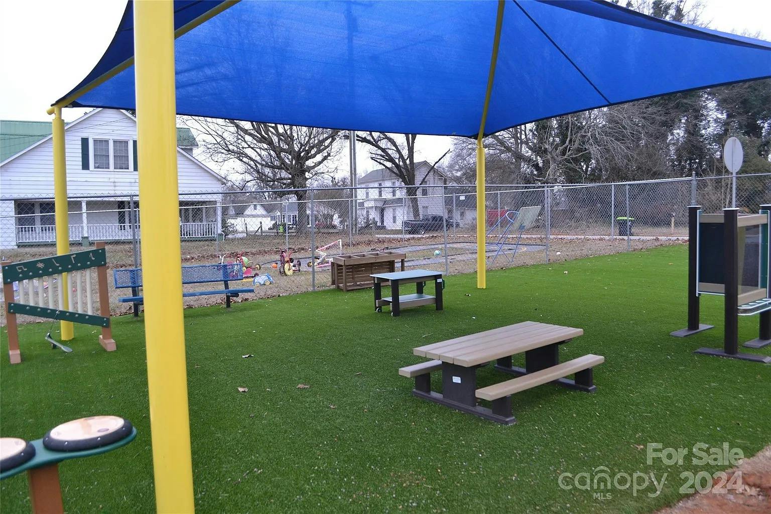 Outdoor play area with blue shade canopy and picnic table