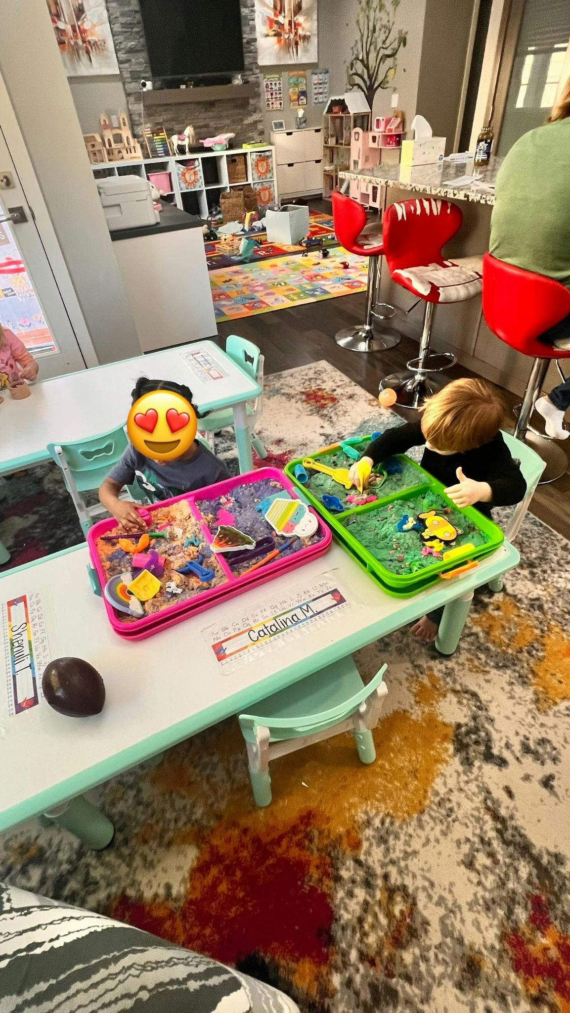 Two children playing with sensory bins at a table