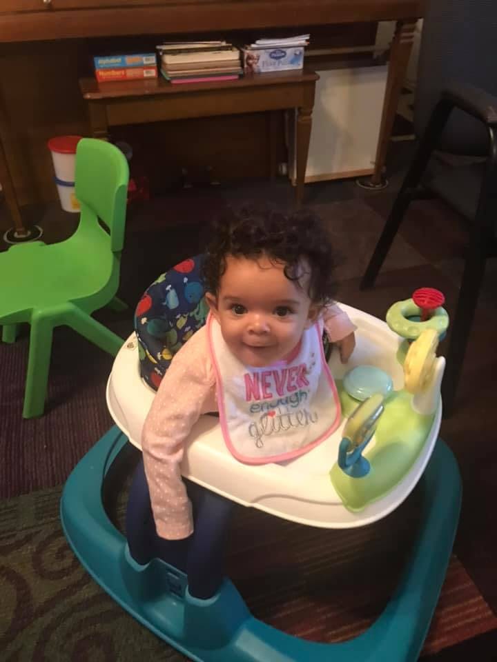 Child in a baby walker wearing a bib