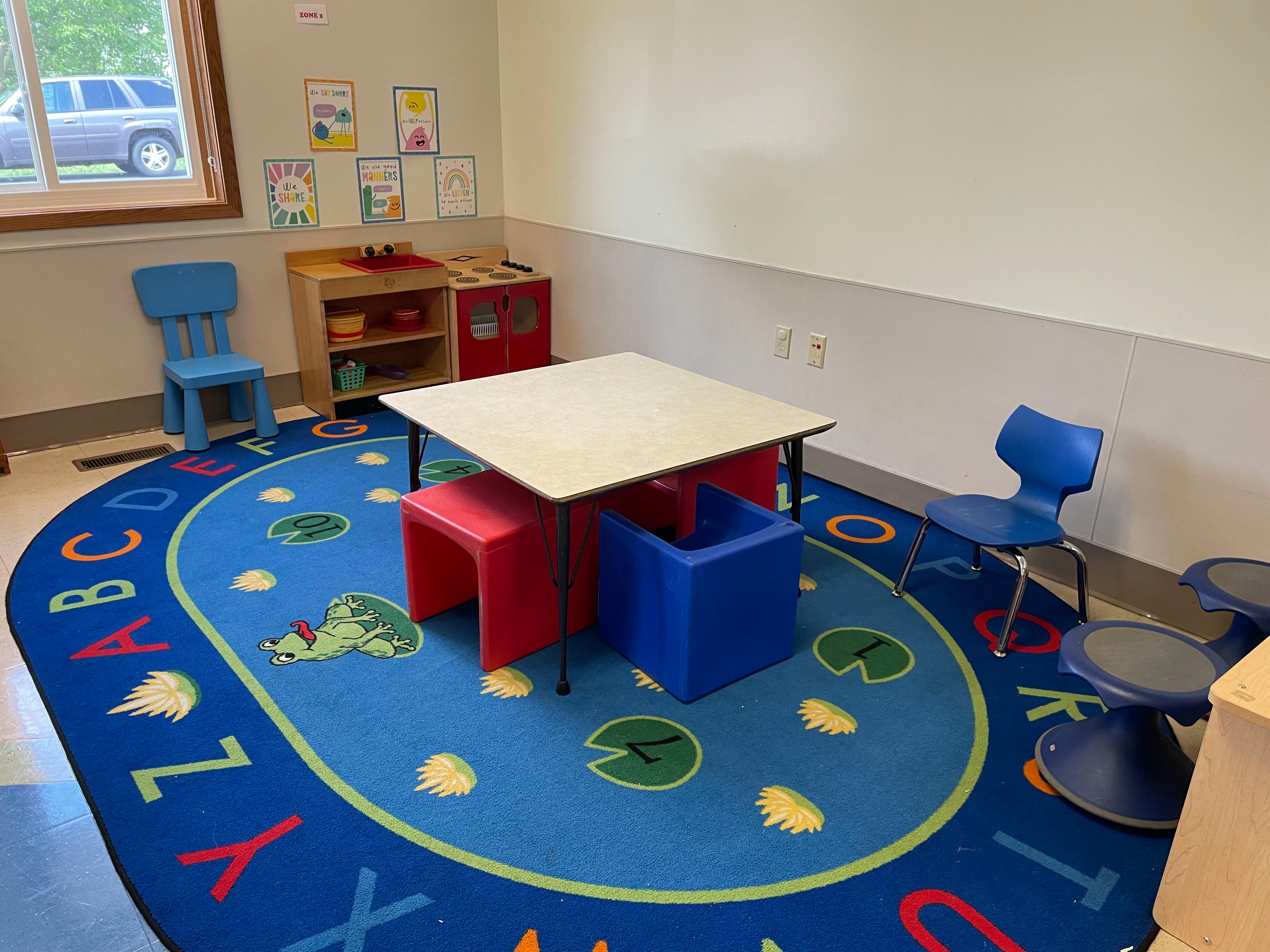 Classroom with small table and chairs on a blue alphabet rug