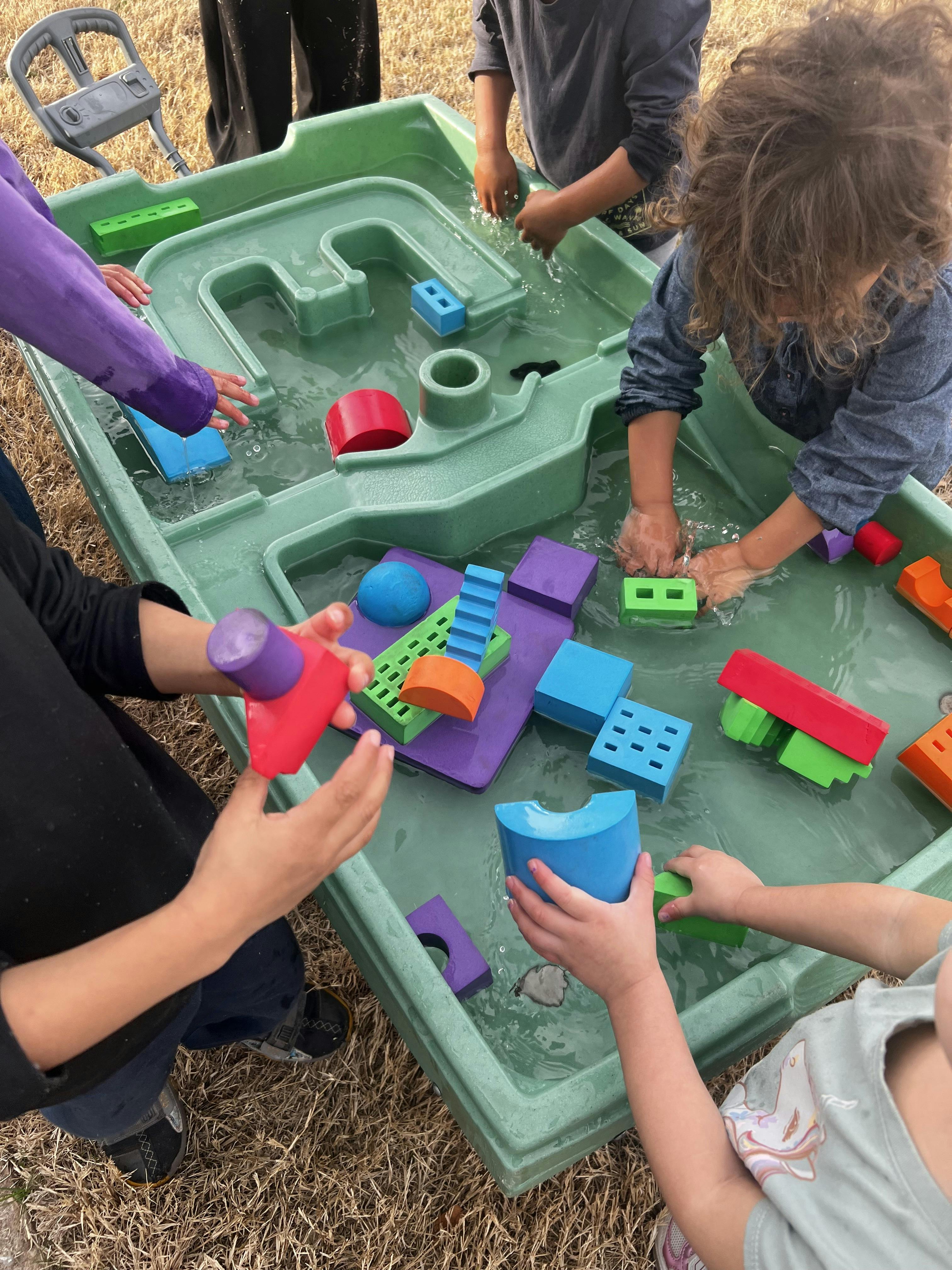 Children playing with colorful blocks in a water table