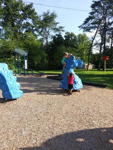 Child climbing on a blue dinosaur playground structure