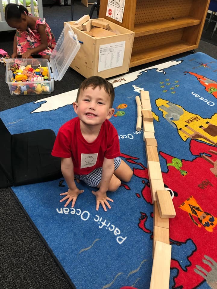 Child kneeling on a world map rug with wooden blocks