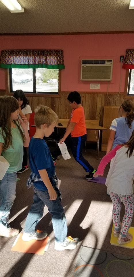 Children standing on colored mats in a classroom