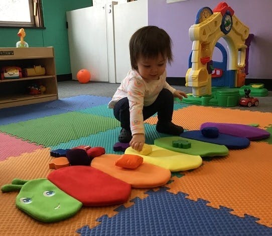 Child playing with colorful caterpillar toy on a mat in a playroom
